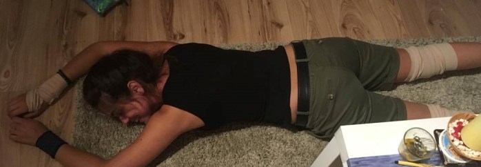 Junge Frau liegt am Boden mit Verbänden an den Gliedmaßen.